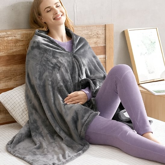 Femme posée sur lit avec couverture chauffante sur elle