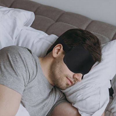 homme dans lit avec masque de sommeil sur yeux